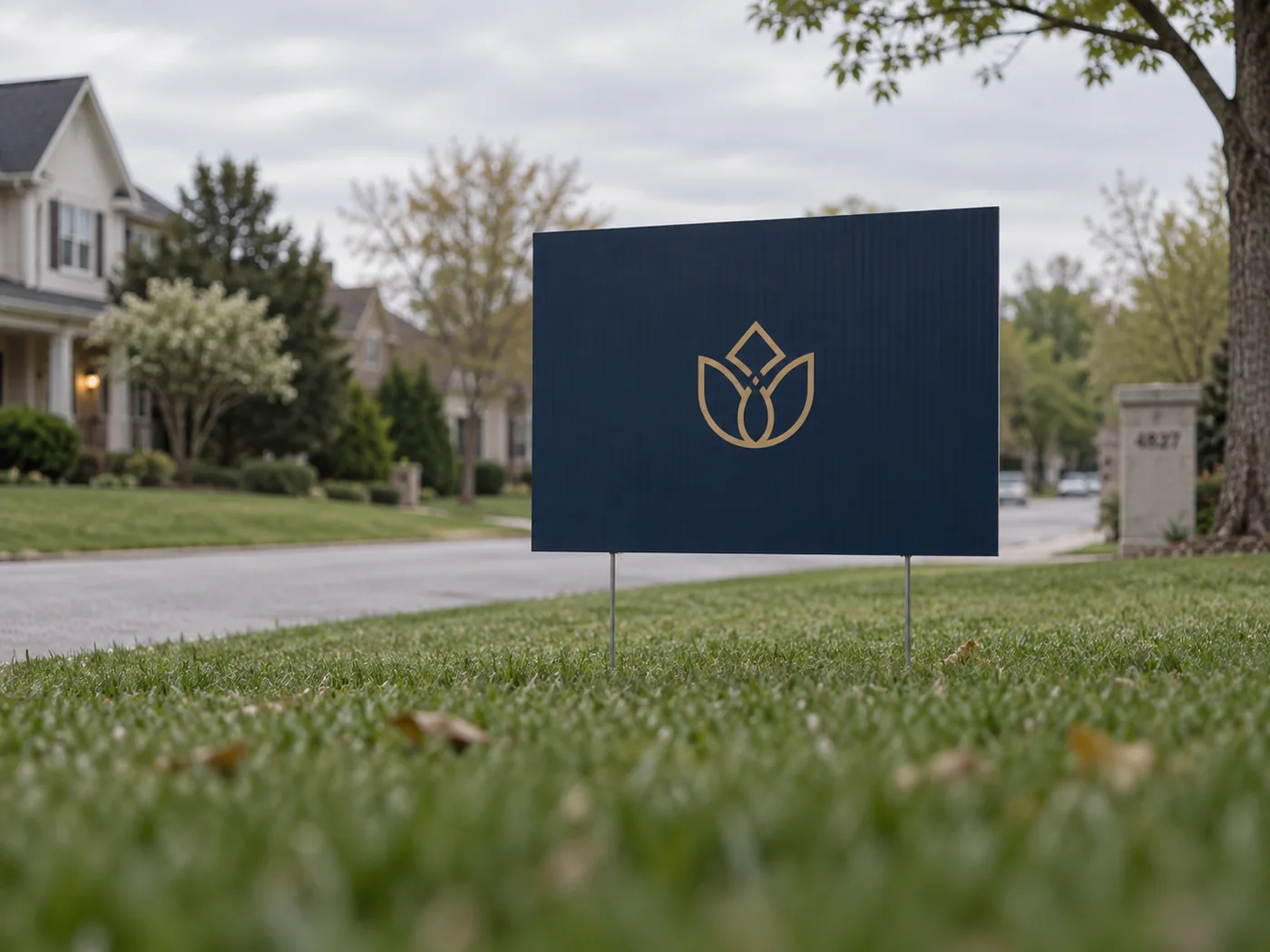 A navy corrugated plastic yard sign on an H stake in a lawn, single colour gold mark, flutes visible across the face